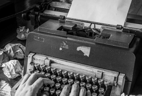 Black and white image of hands on a typewriter to symbolize classic copywriting.